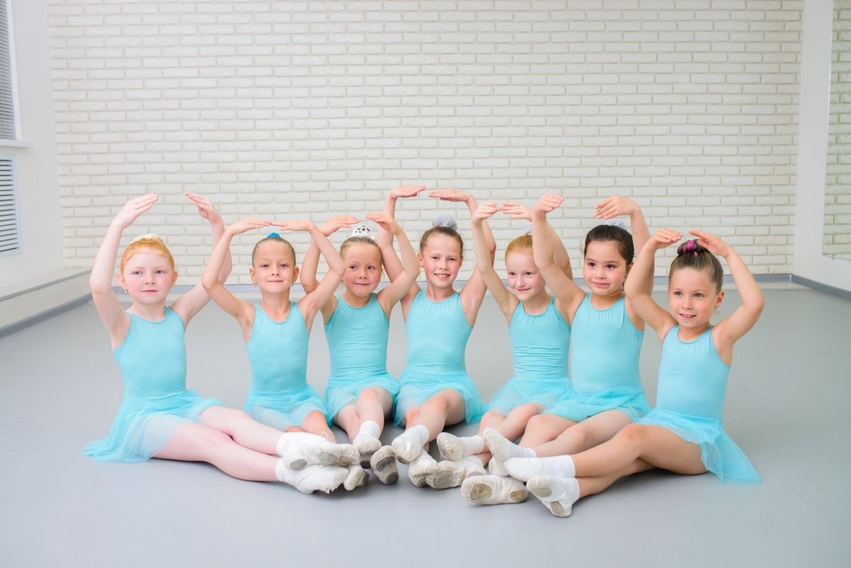 Group of cute little ballet dancers looking at camera at dance school class.